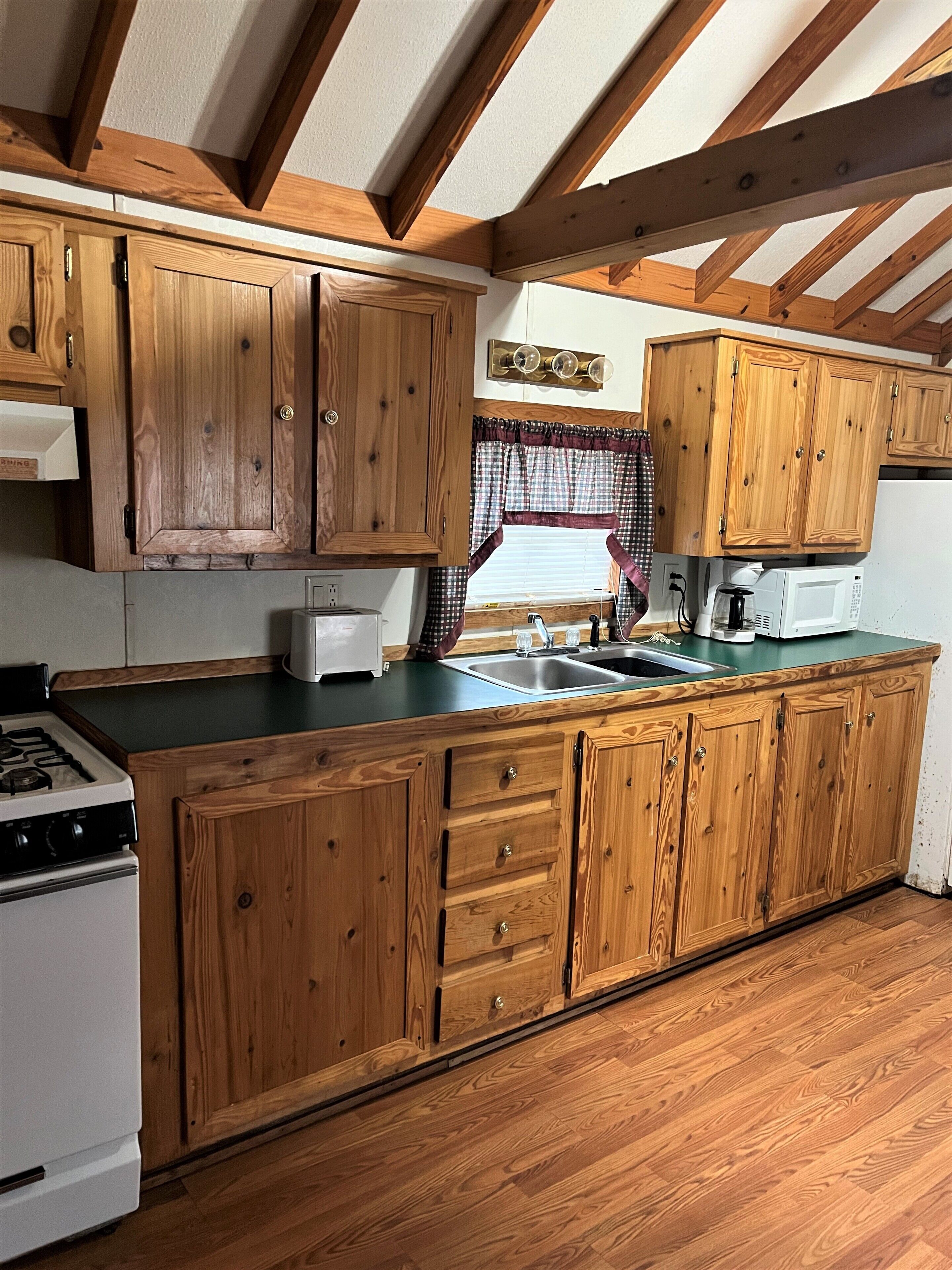 A kitchen with wooden cabinets, a stove, and a microwave.