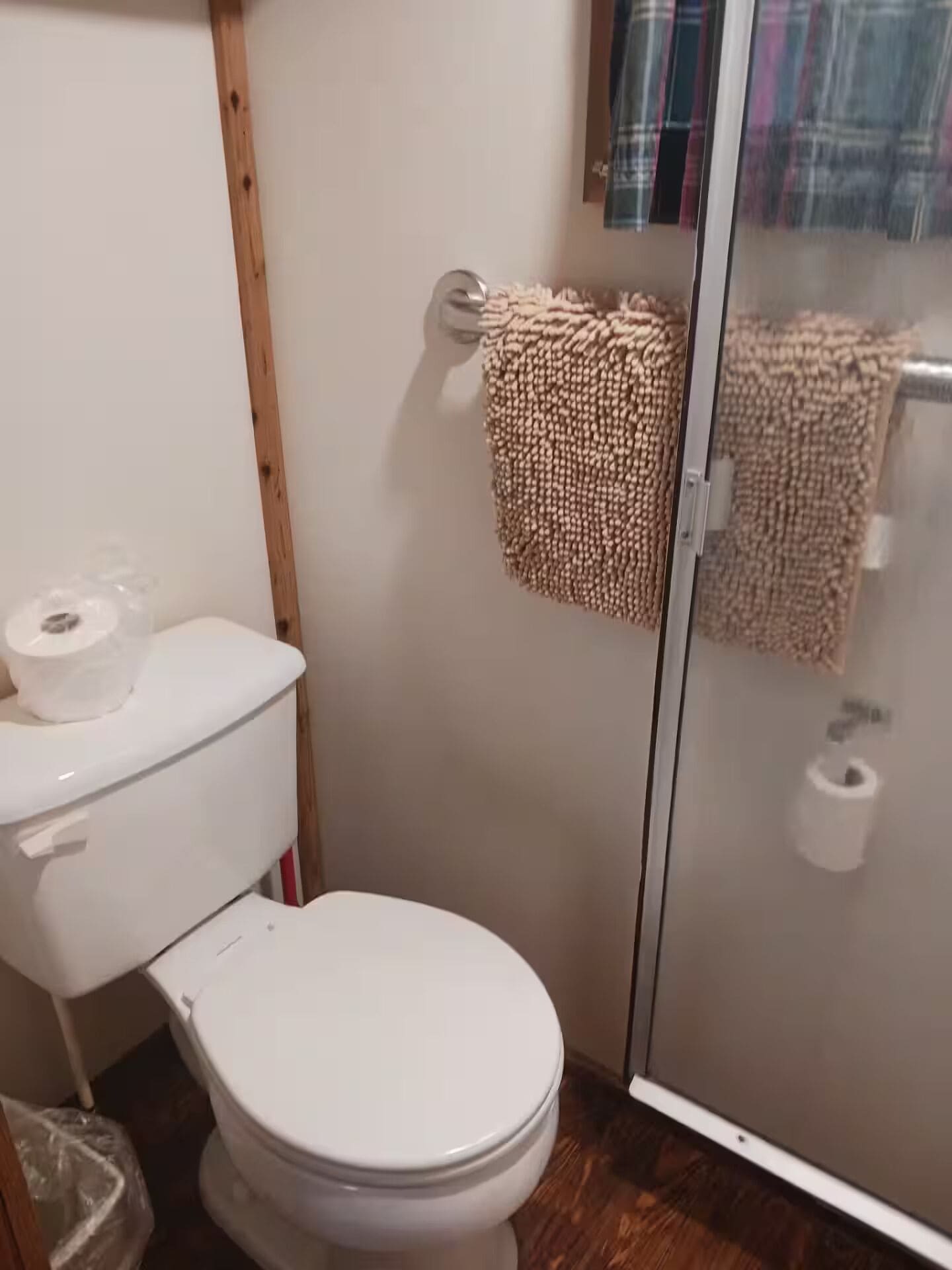 A bathroom with a toilet, a shower enclosure, and a towel rack.