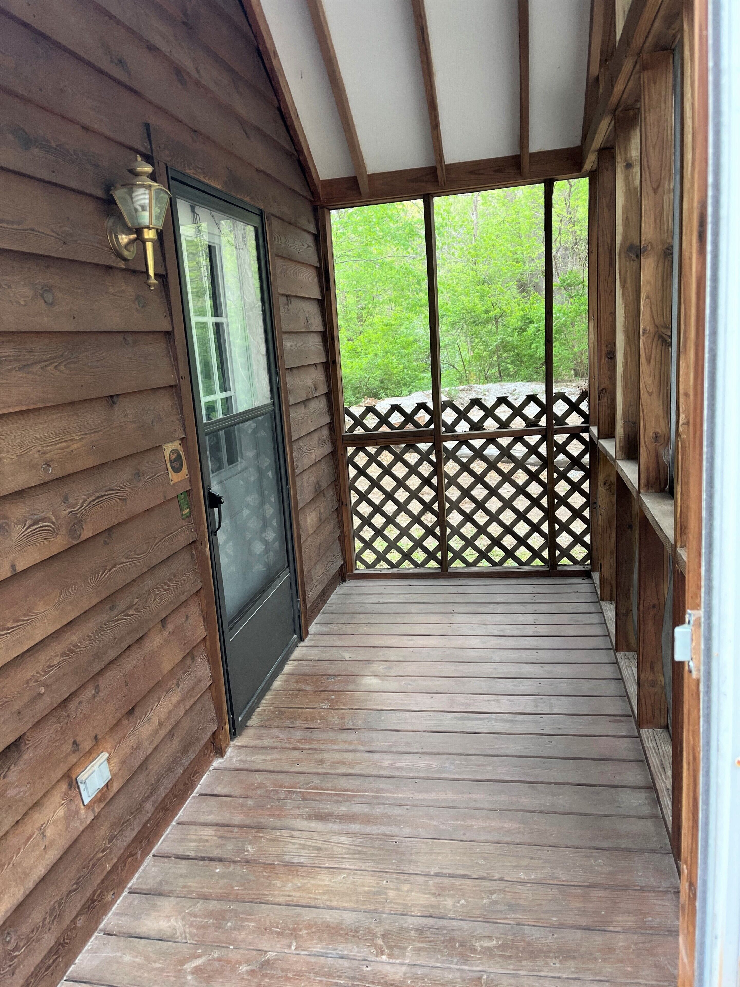 A wooden deck with a lattice fence and a door leading to a covered area.