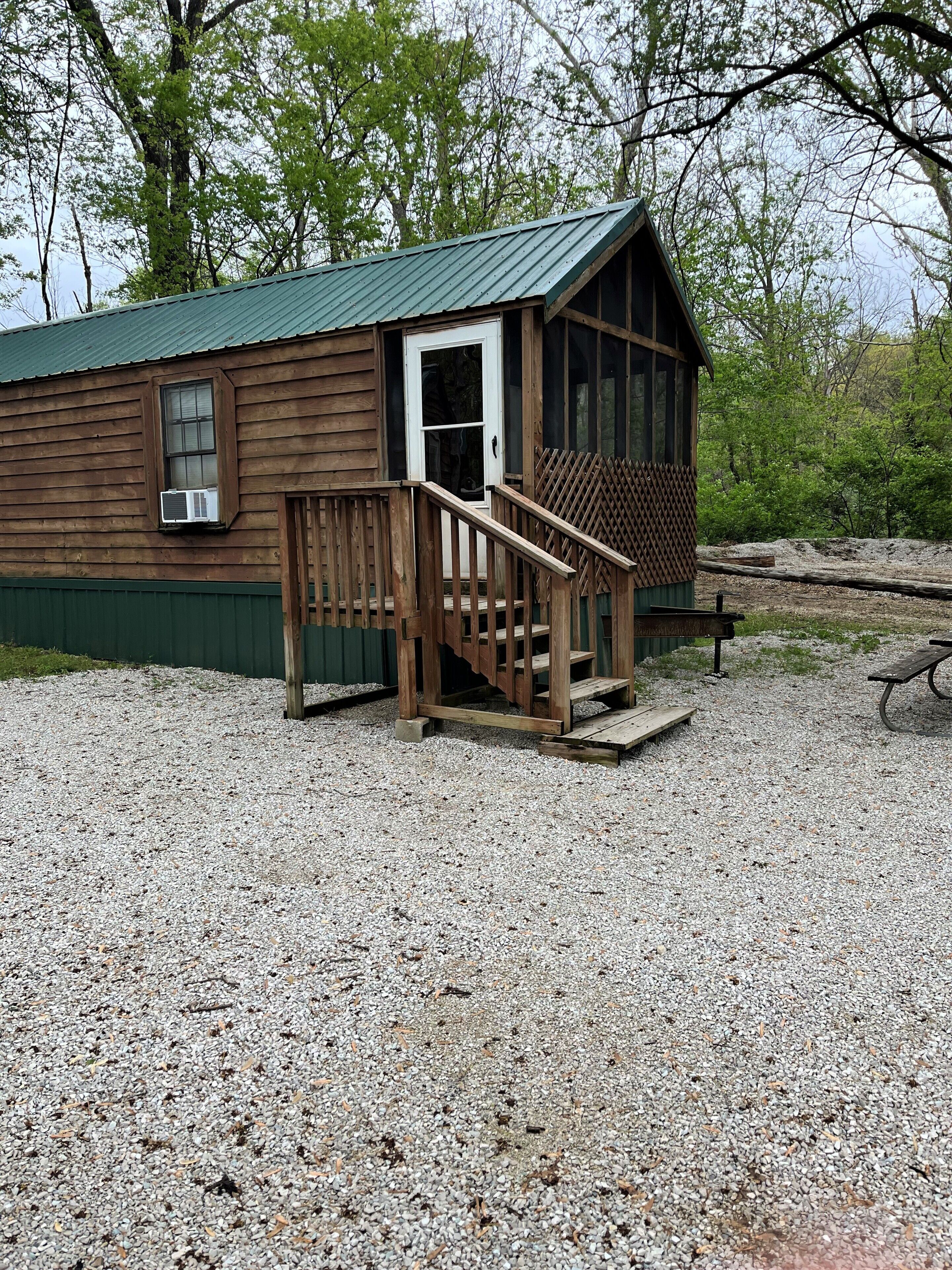 A wooden cabin with a porch, a door, and a window.