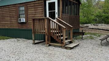 A wooden cabin with a porch, a door, and a window.