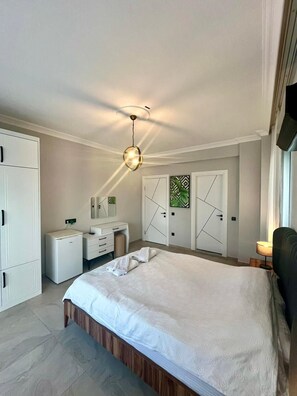 A bedroom with a bed, a desk, a wardrobe, and a ceiling light.
