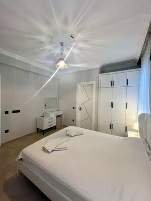 Ein Hotelzimmer mit einem großen Bett, einem Nachttisch, einem Kleiderschrank und einer Deckenleuchte.