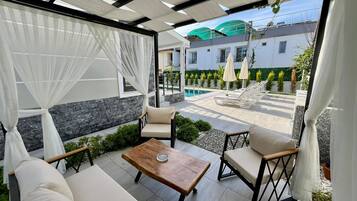 An outdoor patio with a pool, lounge chairs, and a table.