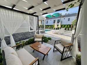 An outdoor patio with a pool, lounge chairs, and a table.