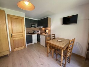 A compact kitchen with a microwave, coffee maker, and a small dishwasher. There is a dining table with chairs and a television mounted on the wall. - Cozy apartment - 4 guests at the foot of the slopes (Arêches-Beaufort)