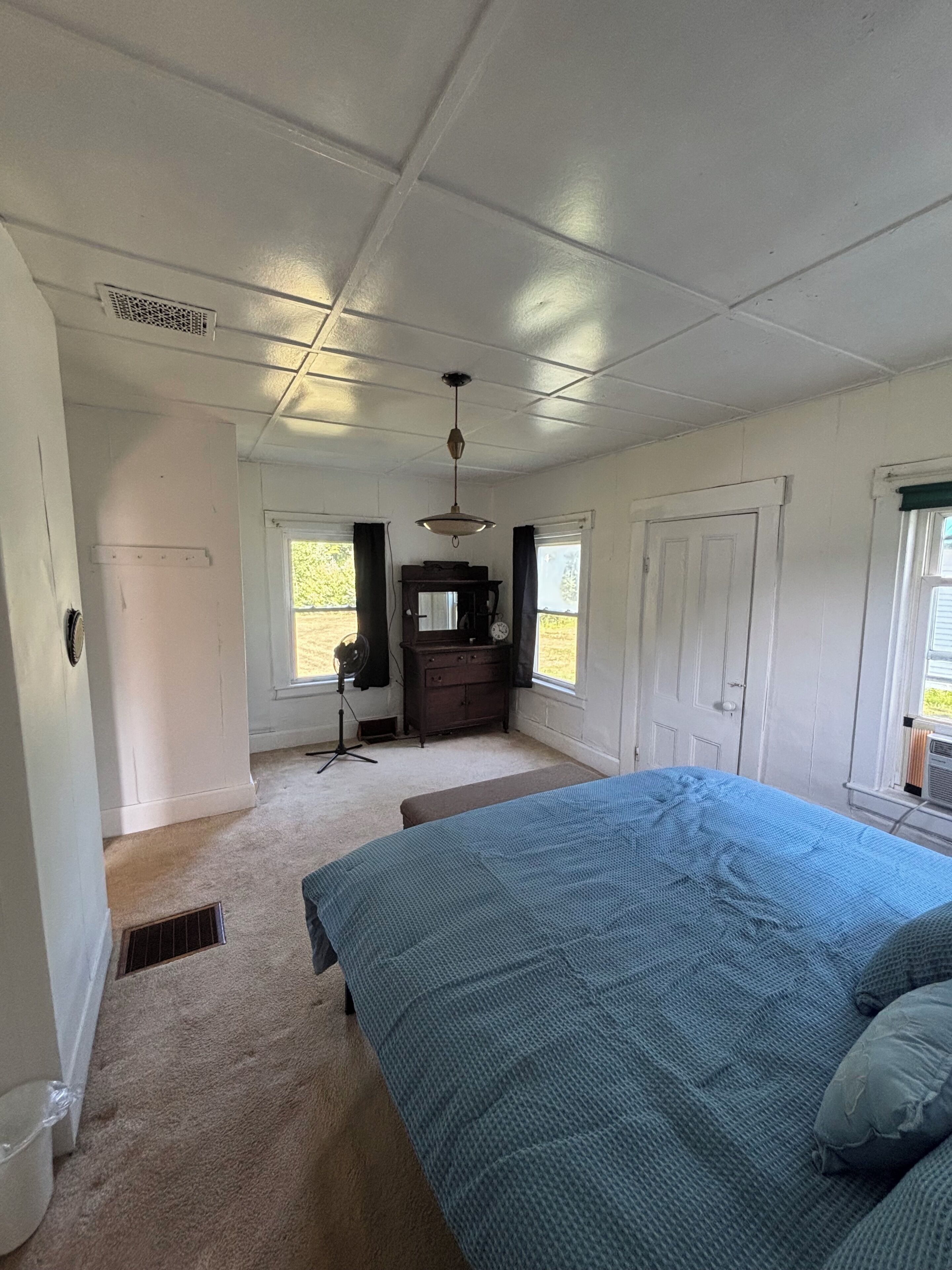 A bedroom with a large bed, a dresser, a desk, and a window.