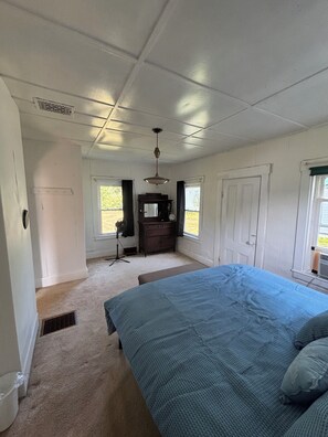 Ein Schlafzimmer mit einem großen Bett, einem Schminktisch, einem Schreibtisch und einem Fenster.