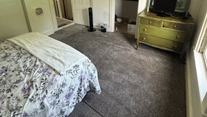 A bedroom with a bed, dresser, and a mirror.