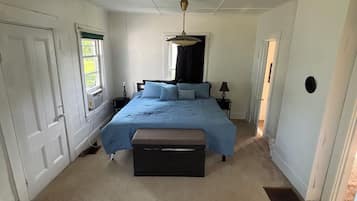 A bedroom with a bed, a bench, a window, and a door.