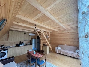 A cozy cabin interior with a dining area, kitchen, and a staircase leading to an upper level.