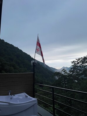 A flag on a pole, a wooden railing, and a mountainous landscape.