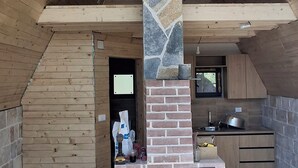 Una cocina moderna con chimenea de piedra, techo de madera y pared decorativa de ladrillo.