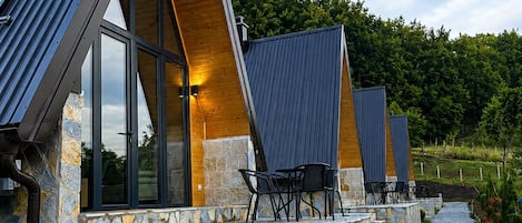 A modern building with a stone facade, large windows, and a gravel pathway leading to outdoor seating.