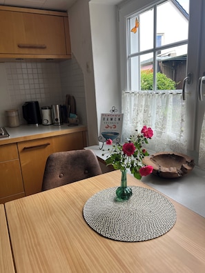 A kitchen with wooden cabinets, a coffee maker, and a book titled 'Ramen Kochbuch' on the counter.