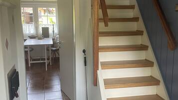 Un escalier avec des marches en bois menant à l’étage supérieur, une porte avec une poignée et un sol carrelé.