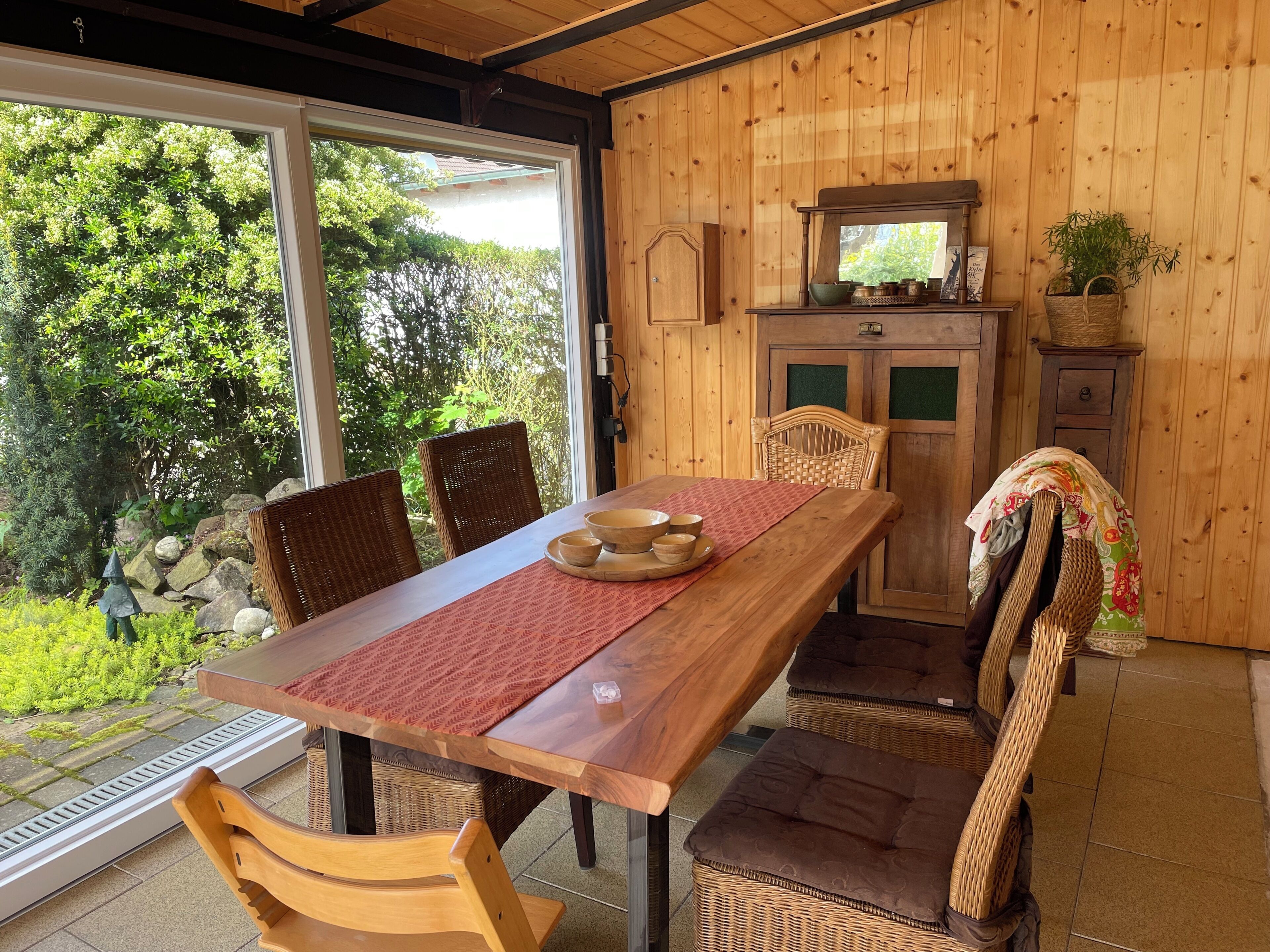 Un coin repas en bois, avec une table, des chaises et une vue sur la verdure environnante.
