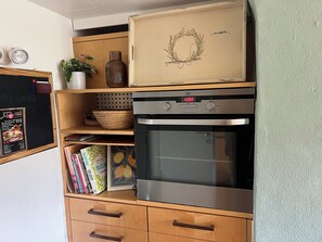 A kitchen with a built-in oven, a chalkboard menu, and a decorative vase.