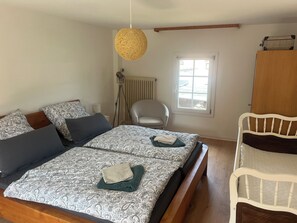 A bedroom with a bed, bedside table, lamp, chair, window, and wardrobe.