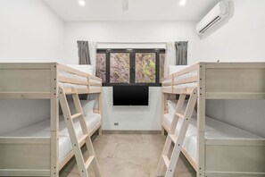 Ein Zimmer mit Etagenbetten, einem Fernseher und einer Klimaanlage.