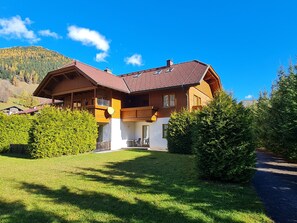 A two-story wooden house with a sloped roof, a balcony, and a well-maintained lawn. - Modern Apartment in Bad Kleinkirchheim (Bad Kleinkirchheim)