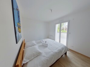 A bedroom with a bed, a painting on the wall, and a sliding glass door leading to an outdoor area. - New apartment in Les Rousses - 6 guests (Les Rousses)