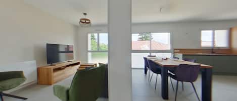 A modern living space with a dining area, a television, and a view of the outdoors.