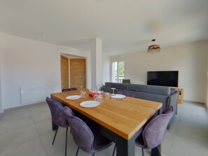 A dining area with a wooden table set for two, surrounded by chairs. - New apartment in Les Rousses - 6 guests (Les Rousses)