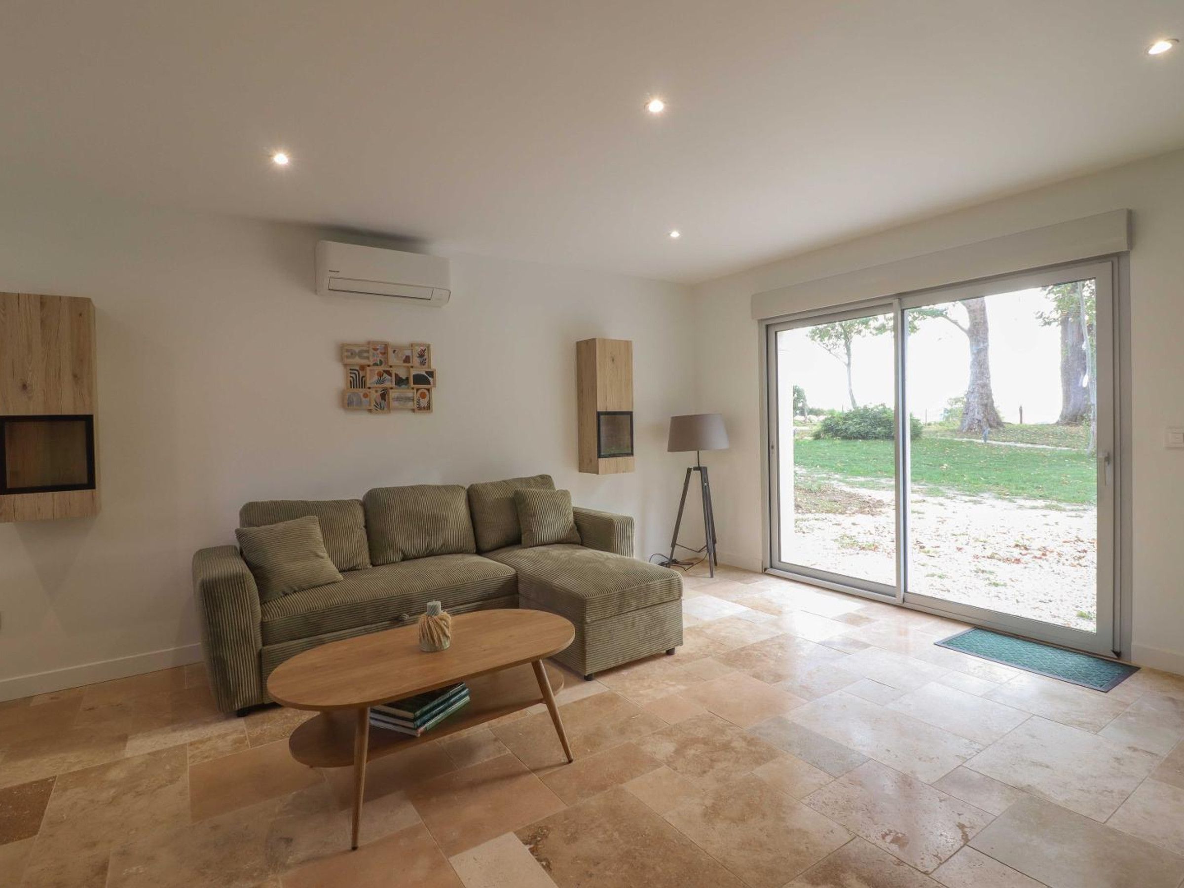Sala de estar con sofá modular, una mesa de centro y una lámpara de pie. Hay un ventanal corredero que da a un espacio exterior.