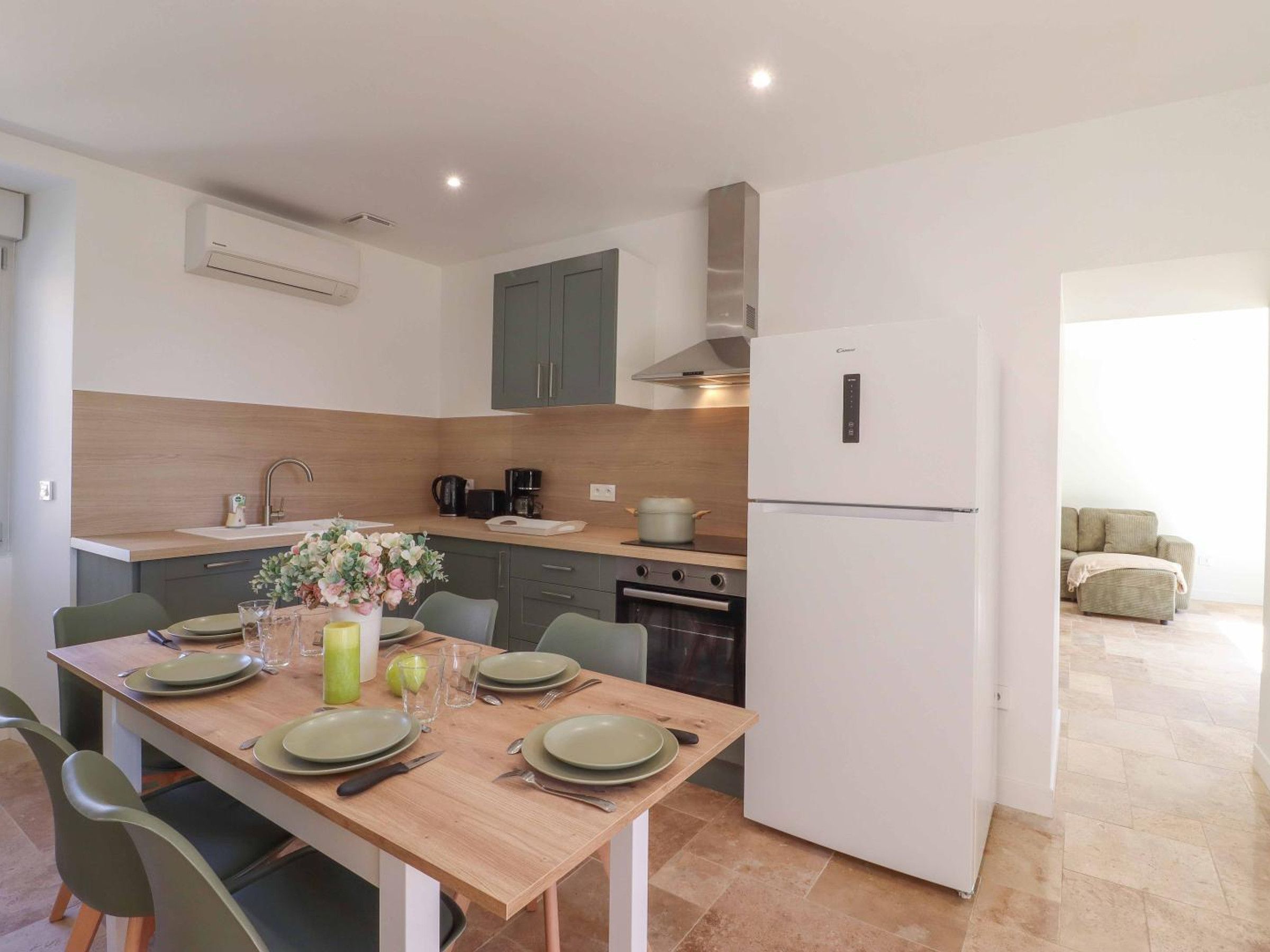 Una cocina moderna con una mesa de comedor para cuatro personas, horno empotrado y refrigerador.
