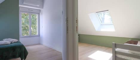 A room with a bed, a skylight, and a window.