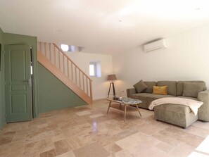 A spacious living area with a staircase, a sofa set, a coffee table, and a lamp.