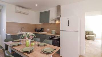A modern kitchen with a dining table set for four, a built-in oven, and a refrigerator.