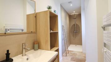 Een moderne badkamer met een wastafel, spiegel, houten planken en een douchegedeelte.