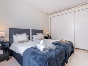 Une chambre d’hôtel avec deux lits, une armoire et une table de chevet avec une lampe.