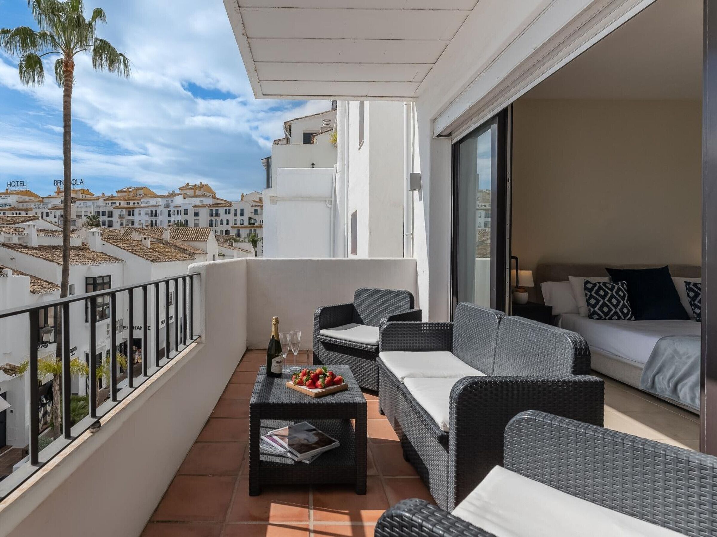 A balcony with wicker furniture, a bottle of champagne, and a fruit basket.