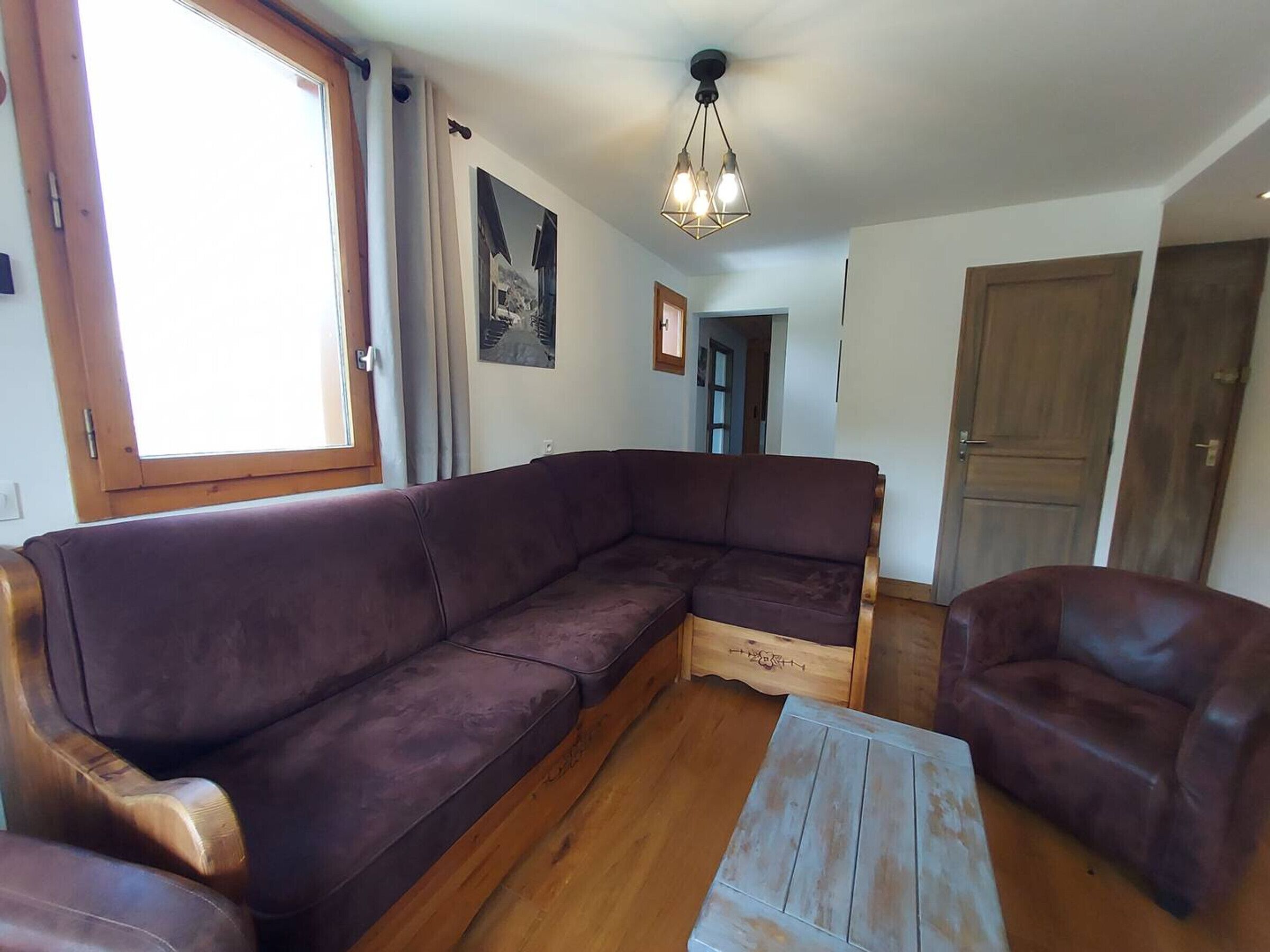 A living room with a sectional sofa, a wooden coffee table, and a wooden door in the background.