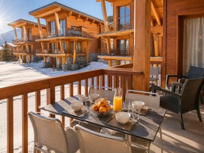 A wooden chalet with a balcony dining area, equipped with tables, chairs, and breakfast items. - Spacious apartment at the foot of slopes - 8 guests (Les Arcs 1800)
