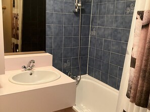 Et badeværelse med en hvid vask, et spejl, et badekar og blå flisevægge.