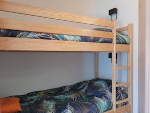 Ein Stockbett mit Holzrahmen und Bettwäsche mit Blattmuster.