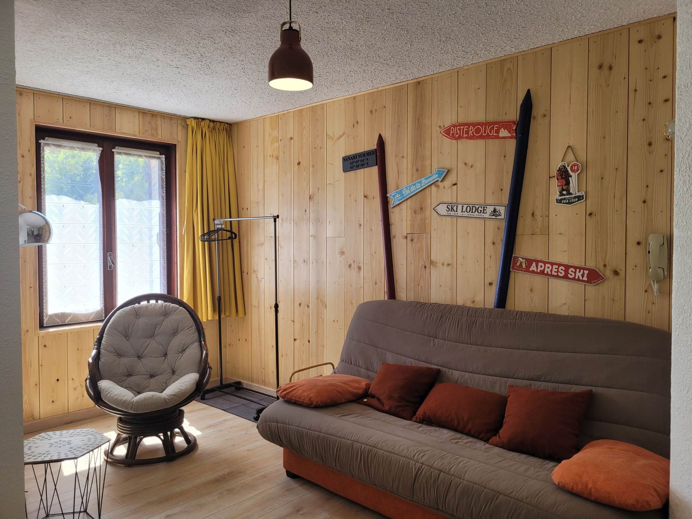 Een gezellige kamer met een bank, een stoel, een klein tafeltje, houten wanden en decoraties met een winters thema.