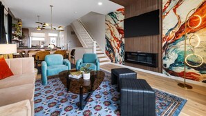 Ein geräumiges Wohnzimmer mit Sofa, Sesseln, Couchtisch und Kamin.