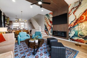 Ein geräumiges Wohnzimmer mit Sofa, Sesseln, Couchtisch und Kamin.