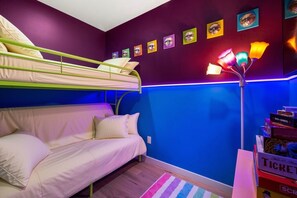 A room with bunk beds, a sofa, a colorful striped rug, and a wall with framed pictures. - Premium Mt. Washington Retreat: VIP Views, Hot Tub, Garage (Pittsburgh)