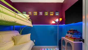 Ein Zimmer mit Stockbetten, blauer Wand, Heizkörper und einem Stapel Brettspiele.
