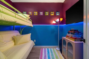 Ein Zimmer mit Stockbetten, blauer Wand, Heizkörper und einem Stapel Brettspiele.