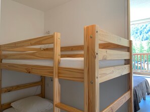 A bunk bed with a wooden frame and white bedding. - Apartment with large terrace - 4 guests (Pra-Loup)