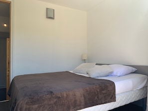 A single bed with a brown blanket, white pillows, and a bedside lamp. - Apartment with large terrace - 4 guests (Pra-Loup)