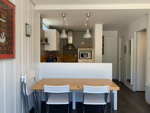 A modern kitchen with a wooden table and two chairs, a microwave, and pendant lights. - Apartment with large terrace - 4 guests (Pra-Loup)