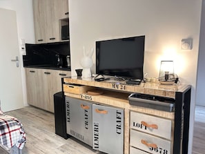 Eine moderne Küche mit Flachbildfernseher, Holzschränken und einer Arbeitsplatte mit Küchengeräten.